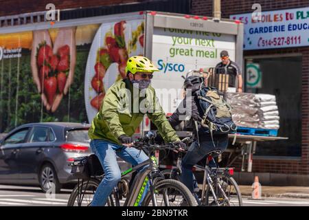 Montréal, CA - 13 mai 2020 : un homme avec un masque facial à vélo pendant la pandémie du coronavirus COVID-19. Banque D'Images