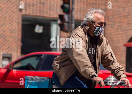 Montréal, CA - 13 mai 2020 : un homme avec un masque facial à vélo pendant la pandémie du coronavirus COVID-19. Banque D'Images