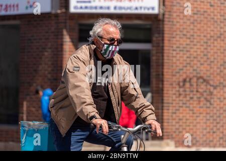 Montréal, CA - 13 mai 2020 : un homme avec un masque facial à vélo pendant la pandémie du coronavirus COVID-19. Banque D'Images