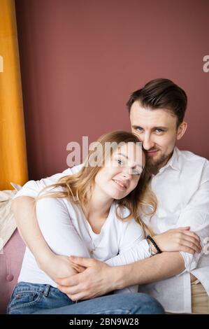 Frère adulte qui embrasse la sœur adolescente. Les deux souriants s'assoient dans la salle de séjour. Banque D'Images