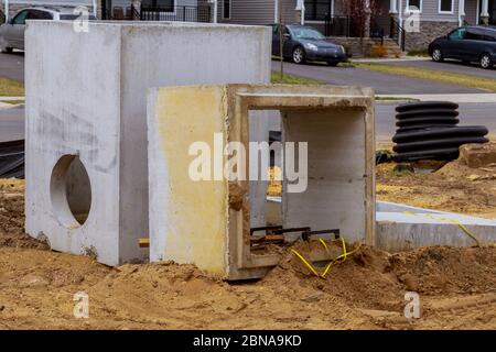 Les blocs carrés en béton avec trou au centre, installés en préparation pour l'égout sous le sol Banque D'Images