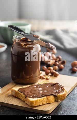 Toaster le pain avec de la pâte de noisette. Crème au chocolat sur planche à découper. Banque D'Images