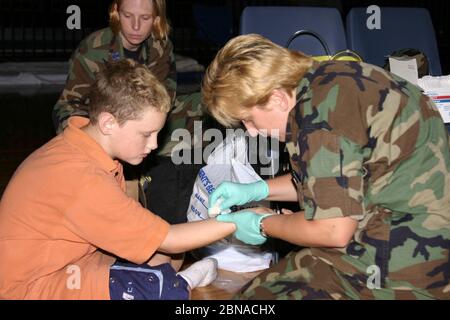 BILOXI, ÉTATS-UNIS - 06 septembre 2005 : le docteur de la Force aérienne traite le bras du garçon à l'abri de l'ouragan Katrina. Banque D'Images