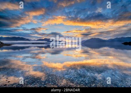 Faisceau lumineux d'atmosphère nuageuse dorée sur le lac te Anau, dans les montagnes d'arrière-plan des monts Stuart et Franklin, Fjordland N Banque D'Images