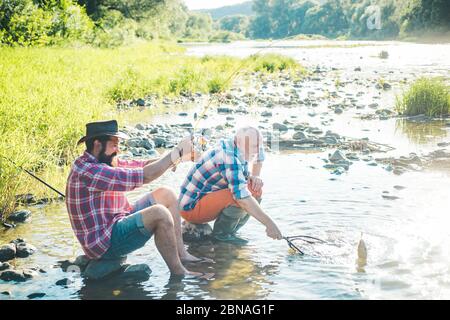 Deux pêcheurs se détendent ensemble tout en pêchant sur le lac le matin. Père à la retraite et fils à barbe mûrs. Je suis l'homme le plus heureux. Deux amis mâles pêchent Banque D'Images