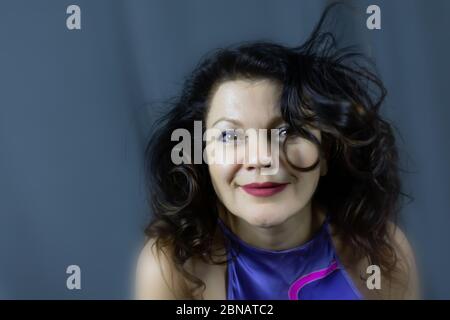 Portrait d'une belle femme d'âge moyen à la mode avec de longs cheveux foncés, posé sur un fond gris foncé. Le concept de la préservation des jeunes à tout ag Banque D'Images