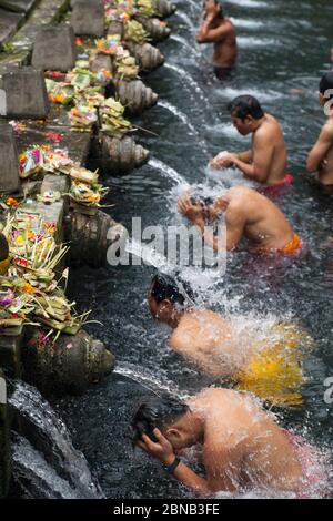 Groupe d'hommes en ligne ayant un bain de purification rituel dans le Temple de l'eau de la Source Sainte (Temple Tor Tirta Empul) pétirtaan (structure de baignade), Bali Banque D'Images
