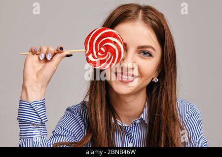 Jeune femme heureuse avec le lollipop regardant la caméra et souriant Banque D'Images