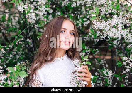 Portrait d'une belle jeune femme en robe blanche en printemps de floraison Banque D'Images