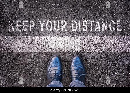 Chaussures avec message « Keep Your distance » écrit sur sol en asphalte Banque D'Images