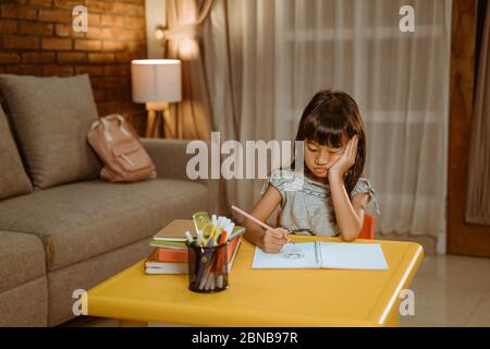 enfant se sent ennuyé pendant ses devoirs à la maison le soir Banque D'Images