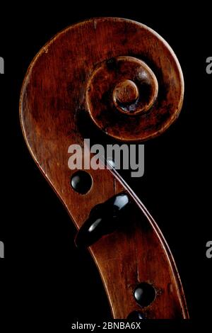 Gros plan des détails sur la tête d'un vieux violon en bois isolé sur fond noir Banque D'Images