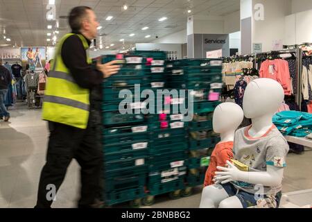 Un membre du personnel qui pousse des plateaux en plastique de marchandises devant des mannequins dans un magasin Marks and Spencer, M&S, au centre de Truro City, dans Cornwall. Banque D'Images