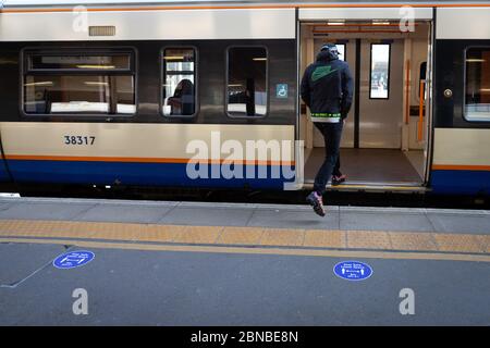 Des autocollants au sol rappellent aux passagers de « laisser un espace » de deux mètres l'un entre l'autre sur la plate-forme. Banque D'Images