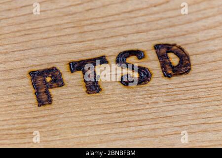 Une abréviation PTSD - syndrome de stress post-traumatique - Burnt à la main sur un panneau plat en bois en diagonale Banque D'Images