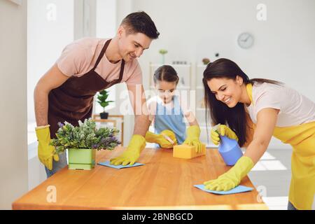 Une famille heureuse nettoie la chambre dans la maison. Mère père et petite fille enfant laver dans des gants tout en s'asseoir sur le sol souriant joyeux. Hygiène W Banque D'Images