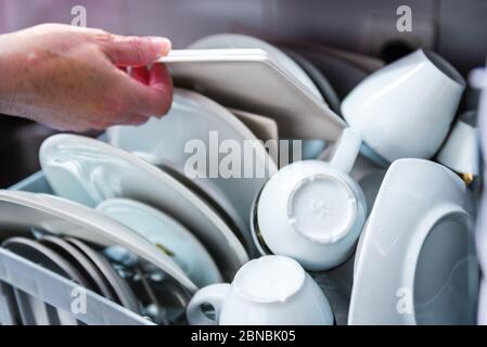 Femme chargeant de la vaisselle et de l'argenterie dans le lave-vaisselle dans la cuisine Banque D'Images