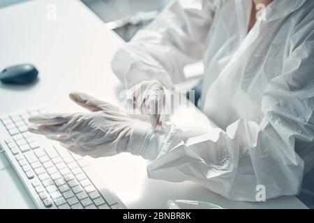 Jeune femme mettant des gants stériles au travail Banque D'Images