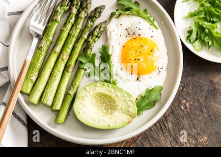 Petit déjeuner maison sain avec asperges, œuf frit, avocat et arugula. Concept de mise en quarantaine saine alimentation. Régime de céto Banque D'Images