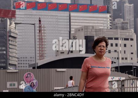 Hong Kong, CHINE. 14 mai 2020. Une femme se promo le long de la promenade du bord de mer à l'extérieur DU CENTRE DES CONGRÈS de WAN Chai, derrière elle, voit une exposition mobile de l'image de plusieurs drapeaux nationaux de la RPC sur le dessus du bâtiment. Les législateurs pro-Beijing de Hong Kong devraient promouvoir la législation de la loi controversée SUR LE DRAPEAU NATIONAL au Conseil législatif de HKSAR le 27 mai-14, 2020 Hong Kong.ZUMA/Liau Chung-ren crédit: Liau Chung-ren/ZUMA Wire/Alay Live News Banque D'Images