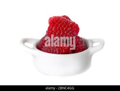 Gros plan de framboises rouges fraîches placées dans un petit bol en céramique sur fond blanc Banque D'Images