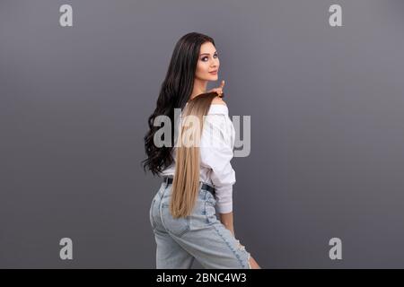 Portrait de mode de la femme tenant des sections de cheveux pour extension sur fond gris Banque D'Images