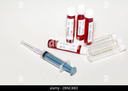 Seringue d'injection avec échantillons de sang et flacons vides sur table blanche pour le test du virus corona Banque D'Images