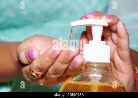 Femme mains en vue rapprochée verser le gel liquide lave-mains pour maintenir l'hygiène comme Covid 19 conscience Banque D'Images