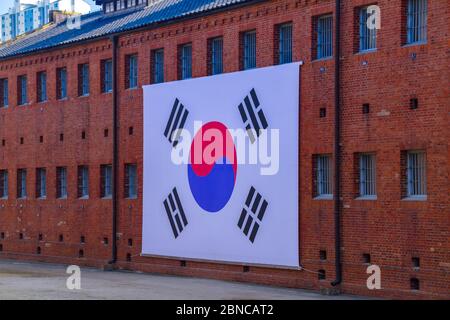 Un grand drapeau coréen accroché devant un bâtiment du Seodaemun prison History Hall, musée et ancienne prison de Seodaemun-gu, Séoul. Banque D'Images