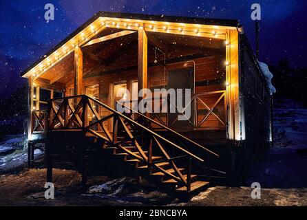 Maison moderne en bois décorée avec des ampoules jaunes en neige à la station de montagne Banque D'Images