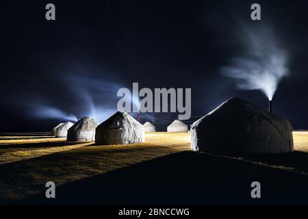 Camp de yourte maisons nomades avec de la fumée de la cheminée à ciel de nuit avec des étoiles en Asie centrale Banque D'Images