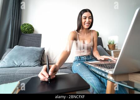 Graphiste femme intelligente travaillant sur ordinateur à la maison - jeune femme dessin avec stylo interactif et ordinateur portable Banque D'Images