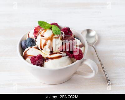 Boules de glace vanille dans un mug avec framboises et bleuets Banque D'Images
