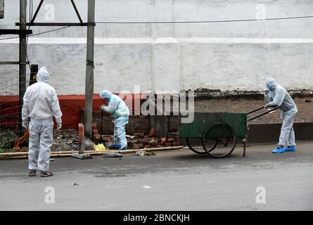 Guwahati, Assam, Inde. 14 mai 2020. Les employés des municipalités dépotent les ordures en portant des vêtements de protection dans la région de Fancy Bazar, pendant le confinement national en cours de la COVID-19, à Guwahati. L'administration du district de Kamrup (Metro) a déclaré une partie de Fancy Bazaar comme zone de confinement et a également fermé le complexe du marché municipal dans la région après que certaines personnes ont été testées positives avec l'infection à coronavirus. Crédit : David Talukdar/ZUMA Wire/Alay Live News Banque D'Images