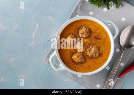 Soupe de crème de citrouille avec boulettes de viande dans un bol sur fond bleu clair, format horizontal, gros plan Banque D'Images