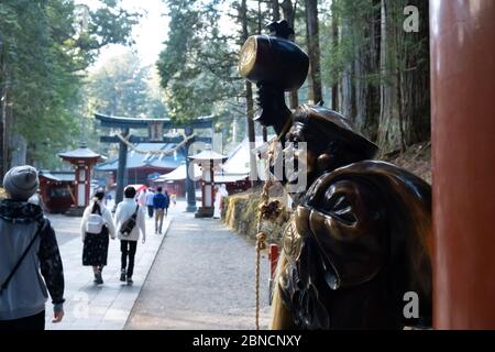 Tochigi, Japon - 21 mars 2019 : vue sur la porte avec la sculpture du voyageur Saint doré de Nikko Futarasan jinja, un sanctuaire de Shinto au sommet de la montagne avec Banque D'Images