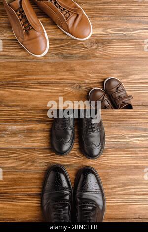 Image divisée avec des chaussures marron et noires pour hommes et enfants sur fond de bois, concept de fête des pères Banque D'Images