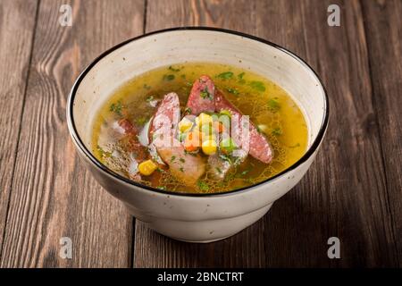 Soupe de pois avec viandes fumées dans une assiette sur fond de bois. Banque D'Images