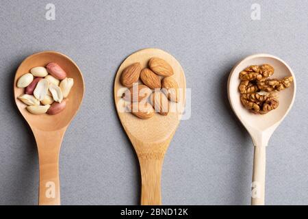 Trois cuillères en bois avec amandes, arachides et noix. Vue de dessus Banque D'Images