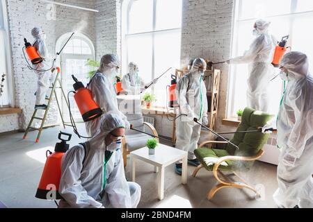 Pandémie de coronavirus. Un désinfectant en costume et masque de protection vaporise des désinfectants à la maison ou au bureau. Protection contre la maladie de COVID-19. Prévention de la propagation du virus de la pneumonie avec des surfaces. Banque D'Images