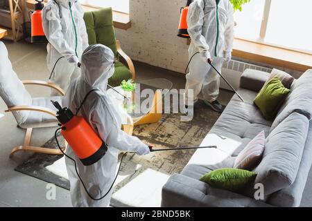 Pandémie de coronavirus. Un désinfectant en costume et masque de protection vaporise des désinfectants à la maison ou au bureau. Protection contre la maladie de COVID-19. Prévention de la propagation du virus de la pneumonie avec des surfaces. Banque D'Images