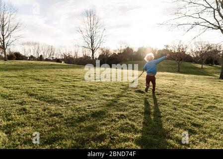 Jeune enfant qui froille dans un champ d'herbe verte Banque D'Images