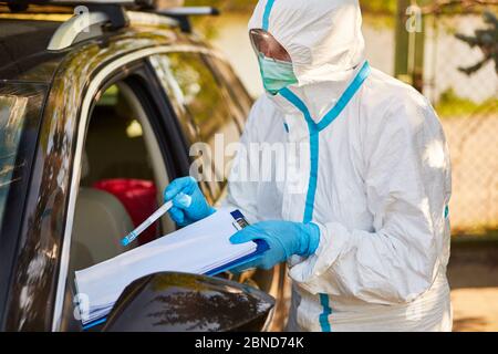 Test du coronavirus avec écouvillon de gorge dans une station d'essai au volant par un scout de confinement du département de santé Banque D'Images