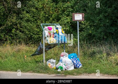 Déversement illégal de sacs à ordures domestiques dans le filet le long de la route destinés à jeter dans des canettes et des bouteilles en plastique, Belgique, août. Banque D'Images