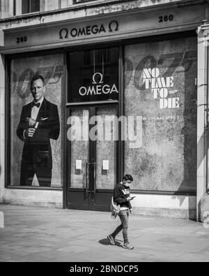 Image monochrome d'une personne dans un masque facial par le signe « pas de temps à mourir » James Bond sur un Regent Street déserté à Londres pendant le verrouillage. Banque D'Images