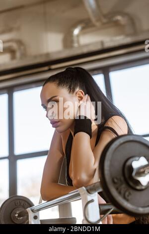 Attention sélective de la belle sportswoman penchée sur la barbell dans la salle de gym Banque D'Images