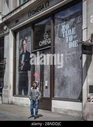 Une personne dans un masque facial par le signe « No Time to Die » James Bond sur un Regent Street déserté à Londres pendant le confinement. Banque D'Images