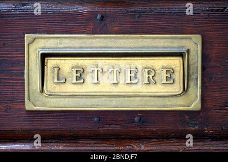 Boîte aux lettres italienne dans une vieille porte sombre. Banque D'Images