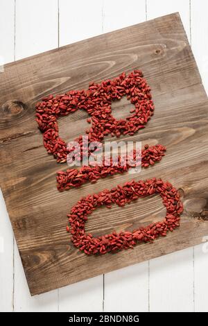 vue de dessus du mot bio fait de baies de goji sur la planche à découper sur une surface en bois blanc Banque D'Images