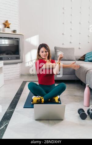 femme faisant du sport sur un tapis suivant des cours en ligne avec un ordinateur portable à la maison Banque D'Images